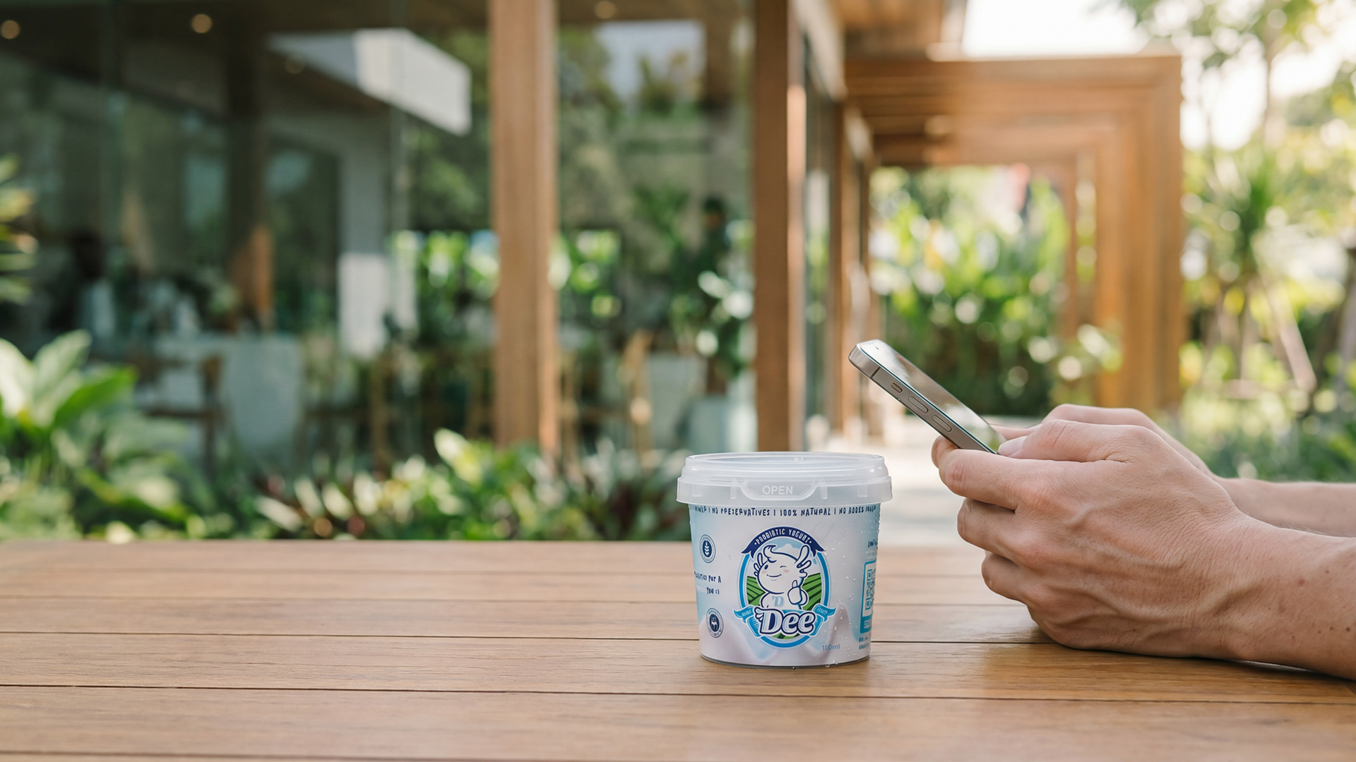 DEE Yogurt cup with phone on wooden table at Phuket café