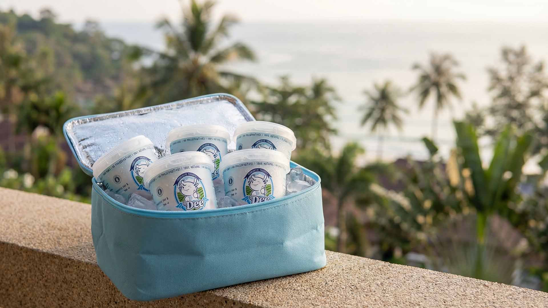 DEE Yogurt cups in cooler bag with Phuket ocean and palm tree view